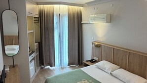 A hotel room with a bed, a desk, a mirror, a wardrobe, and a window with curtains. - Ridvan Hotel (Cesme)