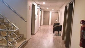 A hotel hallway with wooden flooring, a metal staircase, and doors numbered 206 and 307. - Ridvan Hotel (Cesme)