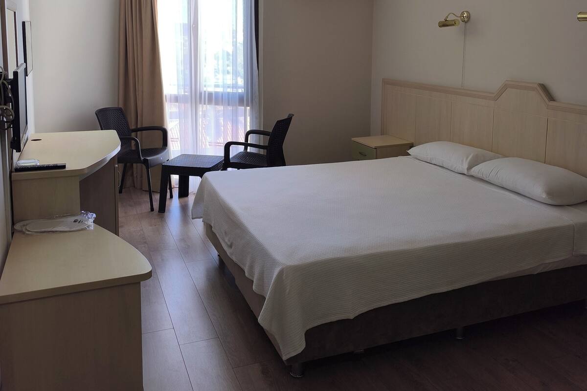 Habitación de hotel con cama, escritorio, silla y equipo de aire acondicionado.