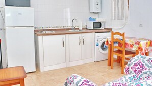 A compact kitchen with a refrigerator, microwave, sink, and washing machine.