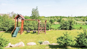 A playground with a slide and climbing structure in a grassy area with trees and rocks. - Cozy home in Postomino with WiFi (Postomino)