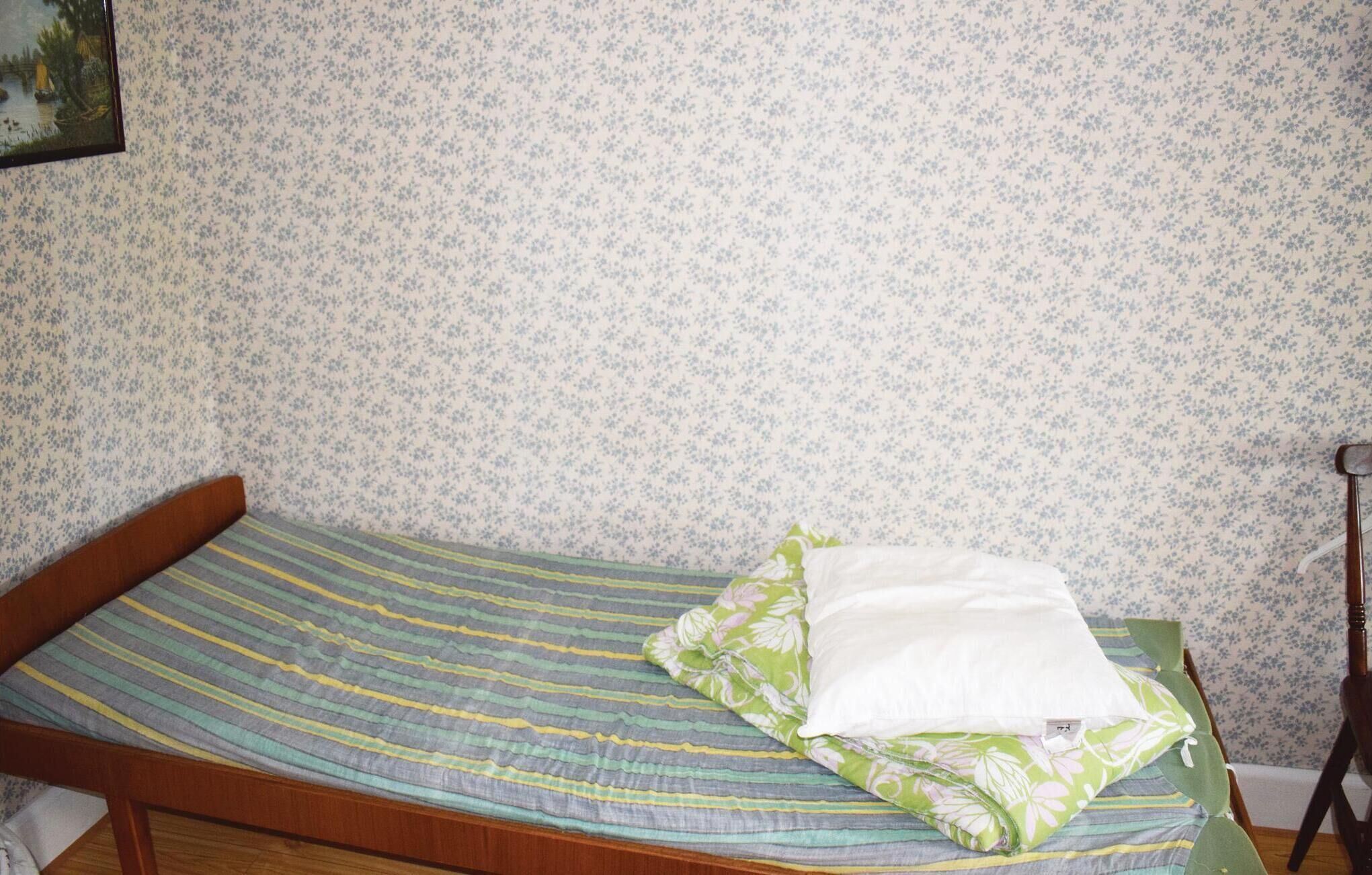 Un lit simple avec une couvre-lit à rayures et un oreiller à motifs floraux.