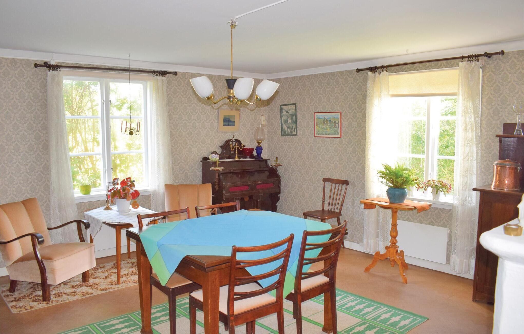 A dining room with a wooden table, chairs, a piano, and a chandelier.