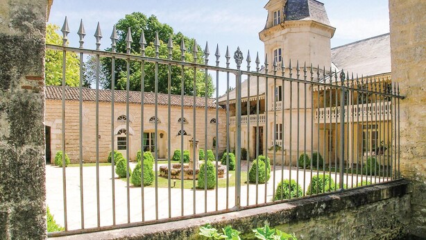 Un patio con un edificio de piedra, una torre y una valla de metal.