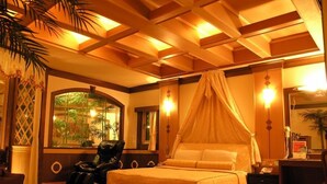 A hotel room with a canopy bed, a massage chair, a large window with a view of greenery, and a minibar. - Swan Lake hotel (Taoyuan City)