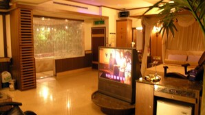 A hotel lobby with a reception desk, a television, a plant, and a decorative window. - Swan Lake hotel (Taoyuan City)