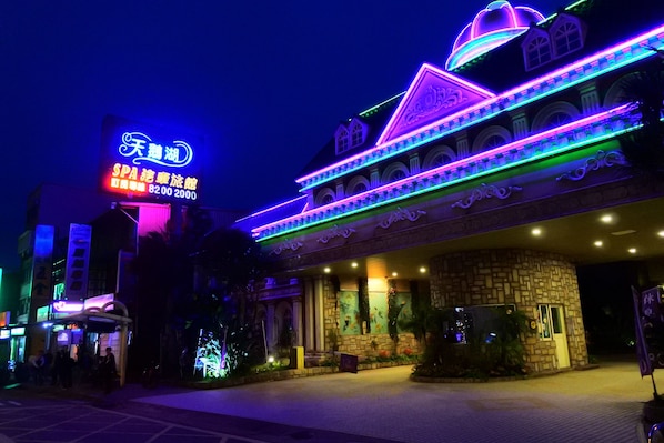 A building with a large illuminated sign, a stone facade, and a series of balconies.