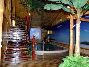A wooden staircase with a decorative railing, a small pool, and tropical plants.