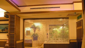 A hotel lobby with a decorative glass partition, a wooden bench, and a reception desk. - Swan Lake hotel (Taoyuan City)