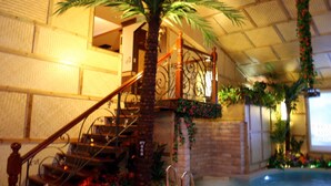 A staircase with a palm tree, a brick wall, and a pool area. - Swan Lake hotel (Taoyuan City)