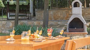 Un espacio exterior para comer con un muro de piedra, una mesa de madera y un horno de piedra.