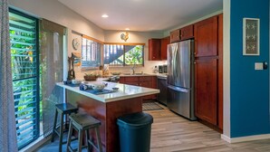 A modern kitchen with a central island, stainless steel appliances, and wooden cabinets.