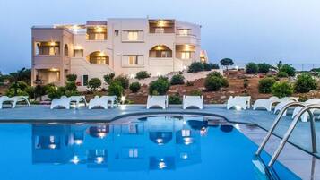 Alberca al aire libre, sombrillas en la alberca y camastros