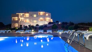 A modern hotel with a swimming pool, multiple balconies, and outdoor seating.