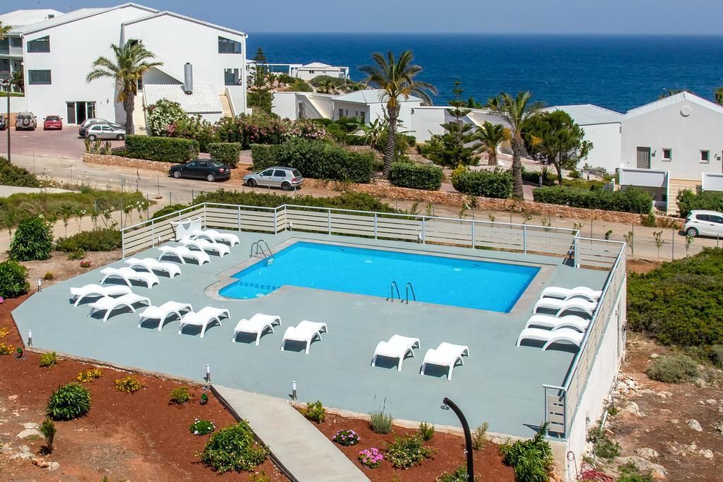 Una piscina al aire libre, sombrillas, sillones reclinables de piscina