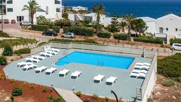 Una piscina al aire libre, sombrillas, sillones reclinables de piscina