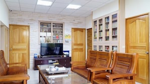A living room with a glass coffee table, wooden chairs, a television, and built-in bookshelves. - Look Tea House (Meishan)