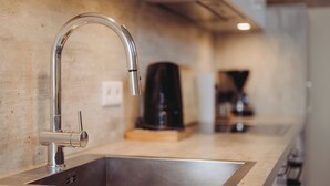 A modern kitchen with a stainless steel sink, a coffee machine, and a sleek faucet. - Wanderreitstation Gut Mischenried (Wessling)