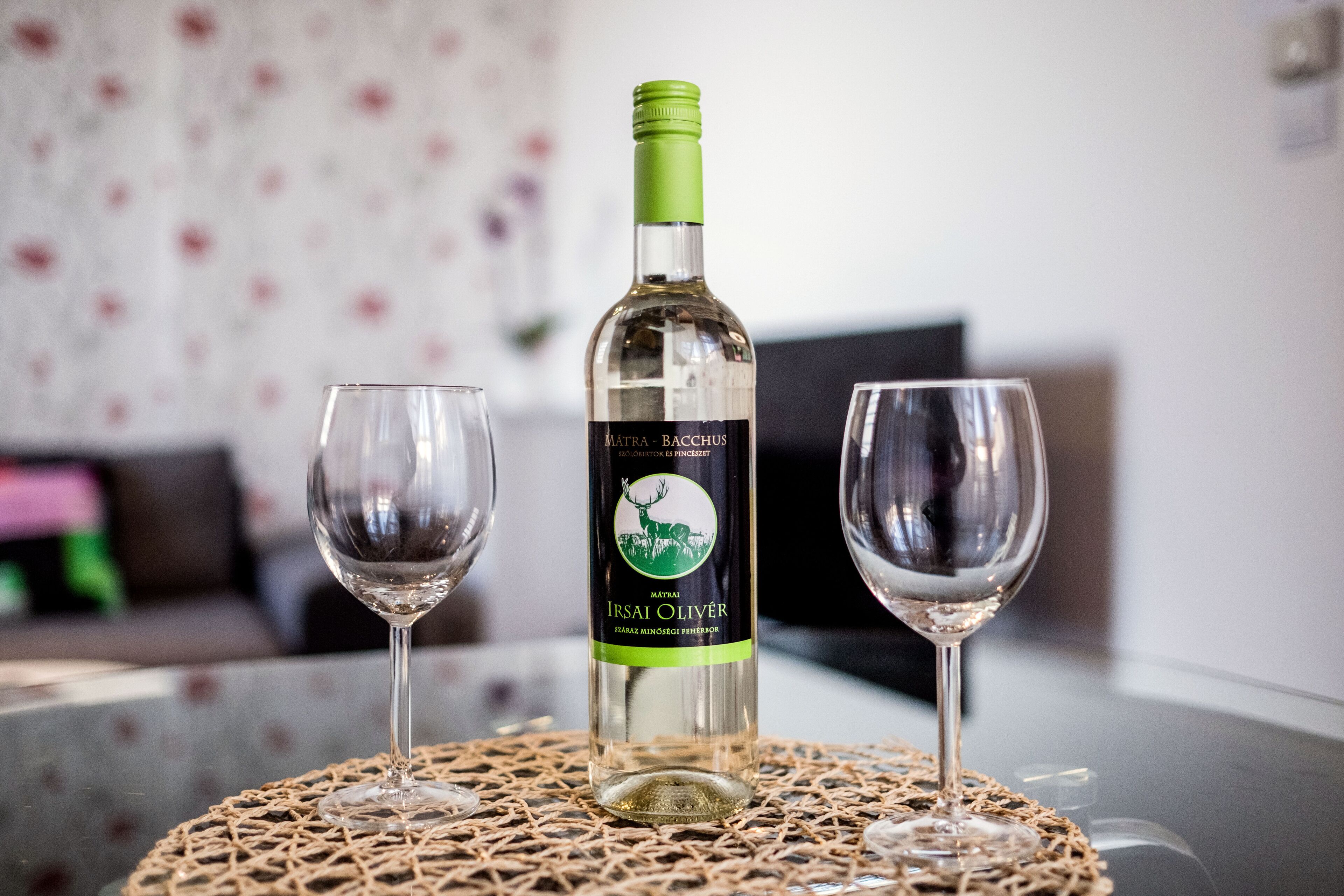 A bottle of Matra Bacchus wine on a table with two glasses.