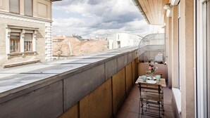 Un balcón con una mesa y sillas, con vista a una obra en construcción y edificios.