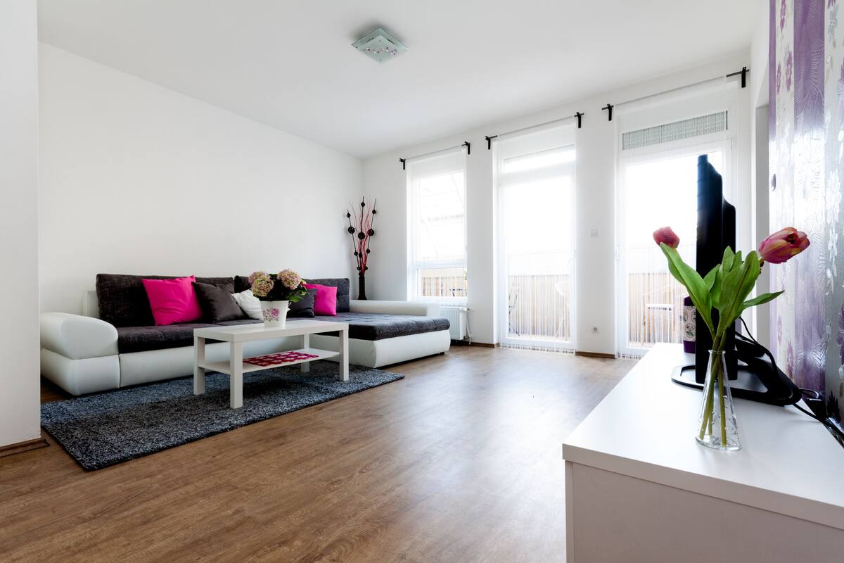 A modern living room with a white sofa, a coffee table, and a vase with flowers.