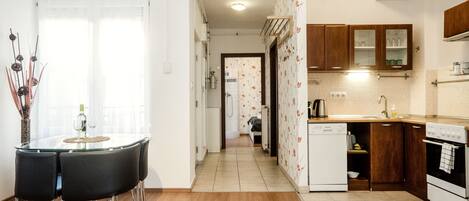 A modern kitchen with wooden cabinets, a dishwasher, and a dining area with a glass table and chairs.