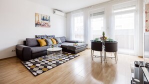 Una sala moderna con un sofá gris, una mesita de centro y un rincón comedor con dos sillas.