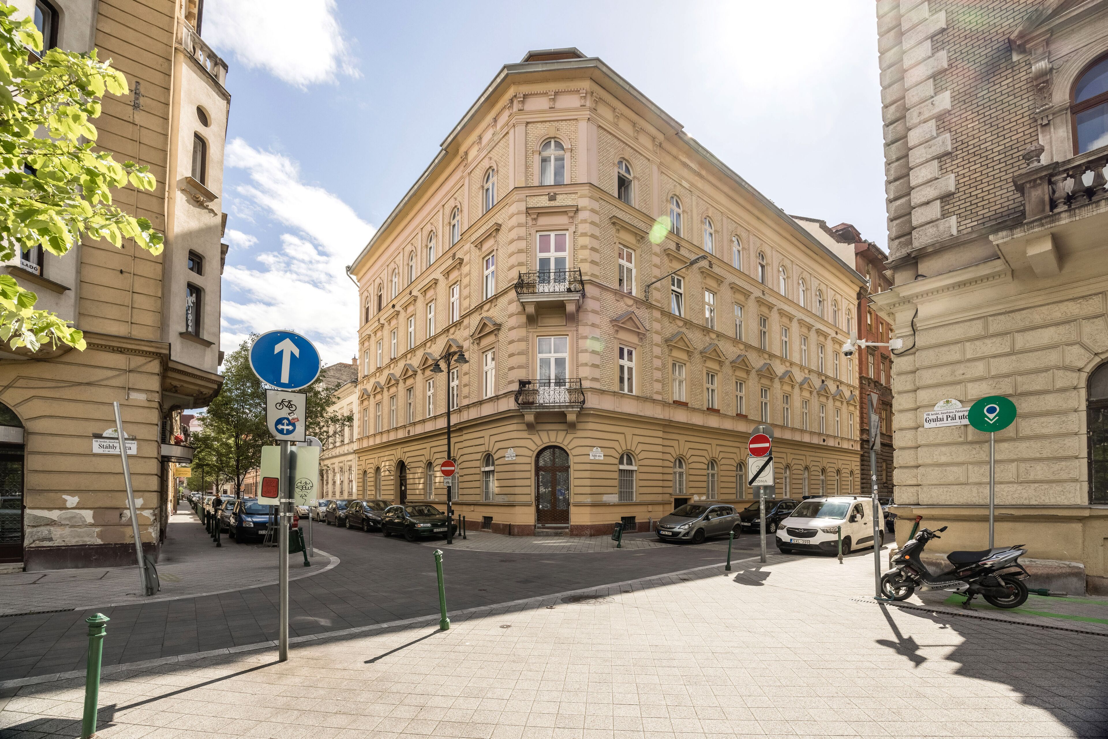Un edificio histórico con entrada en esquina, un letrero de estacionamiento para bicicletas y una señal de dirección.