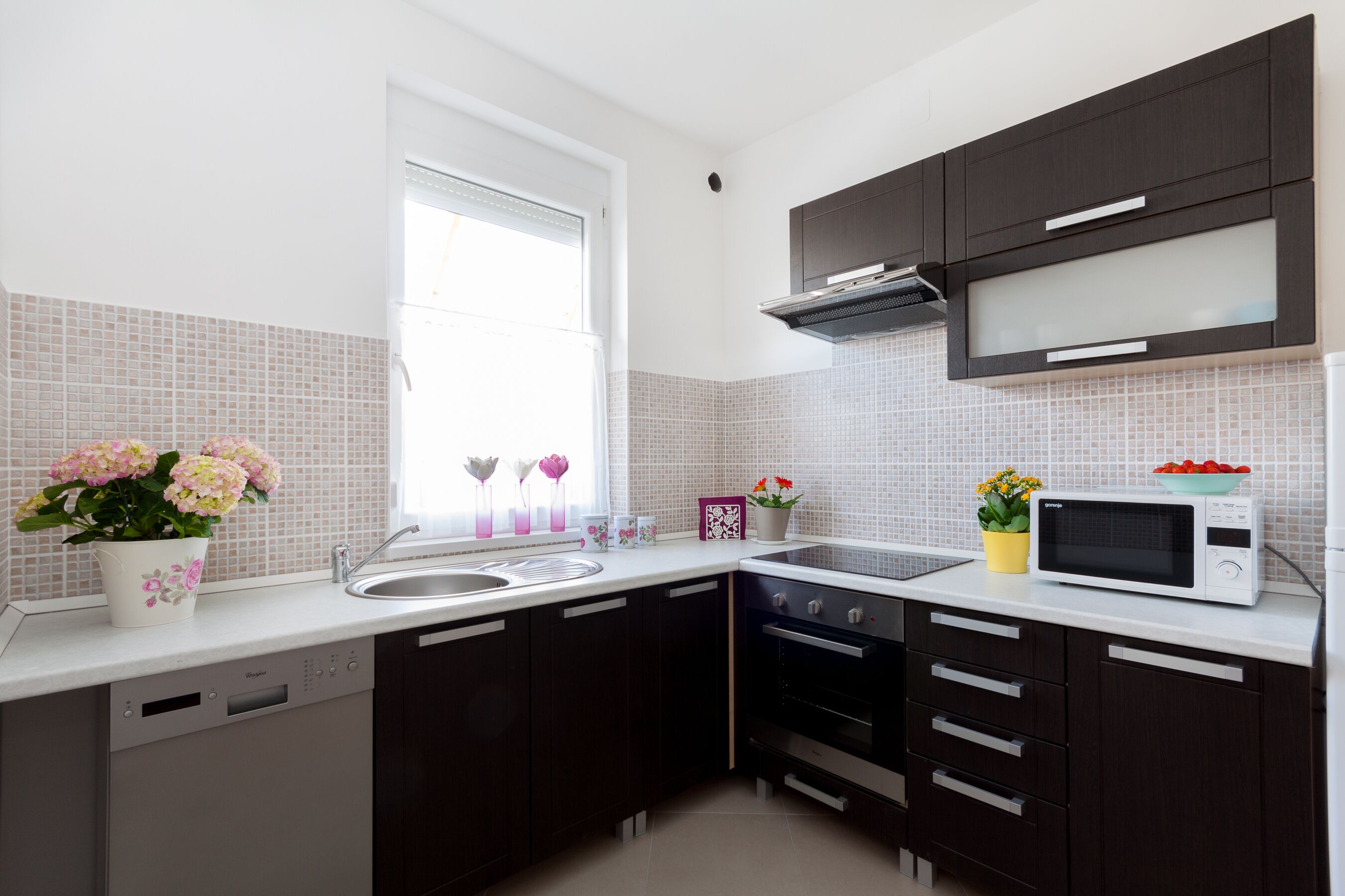 A modern kitchen with dark cabinets, a microwave, and a dishwasher.