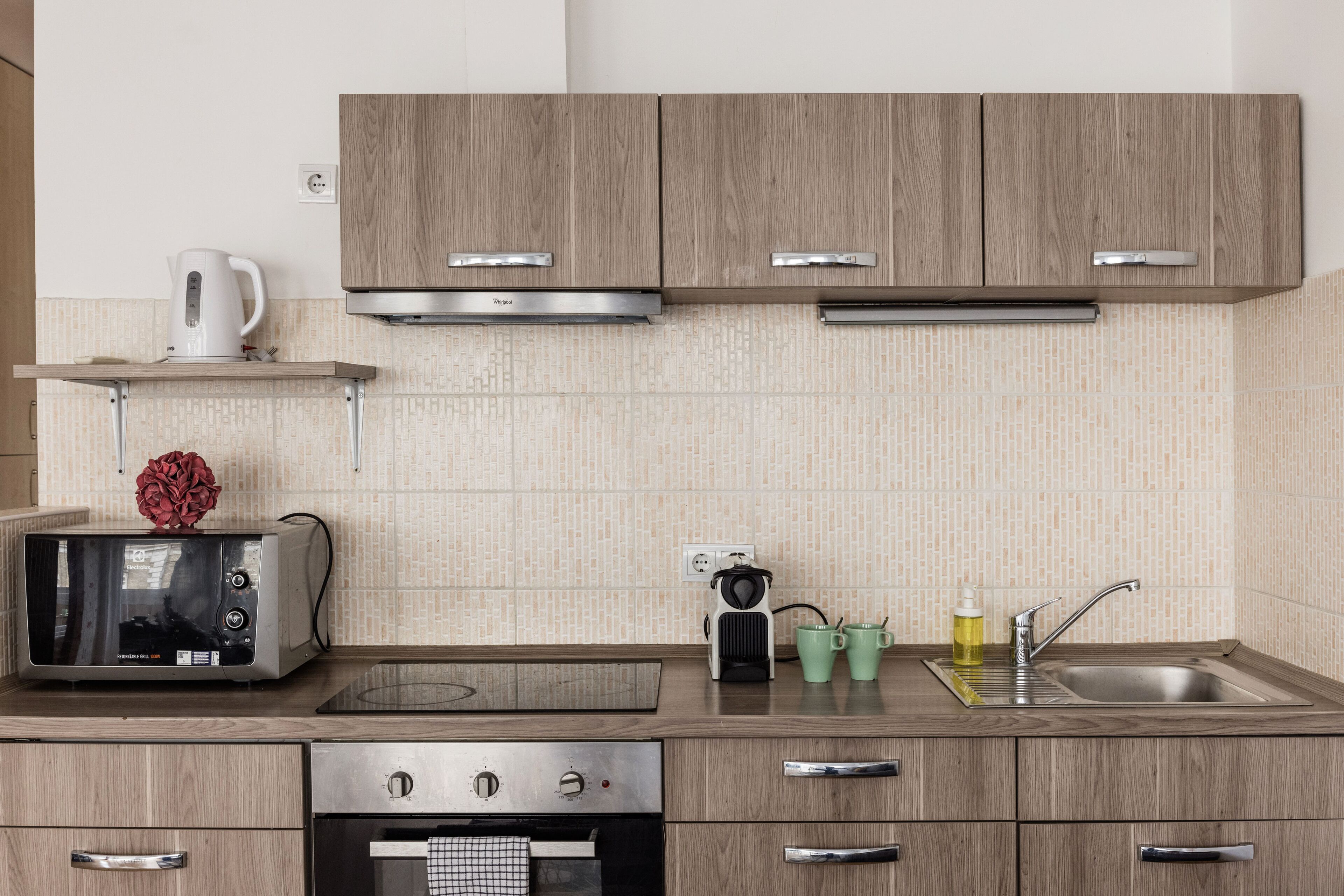 A modern kitchen with wooden cabinets, a built-in oven, a microwave, and a sink.