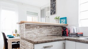 Una cocina moderna con armarios blancos, salpicadero de piedra y una isla integrada.