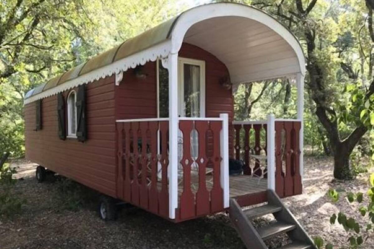 Een rode stacaravan met een witte veranda en een kleine trap naar de ingang.