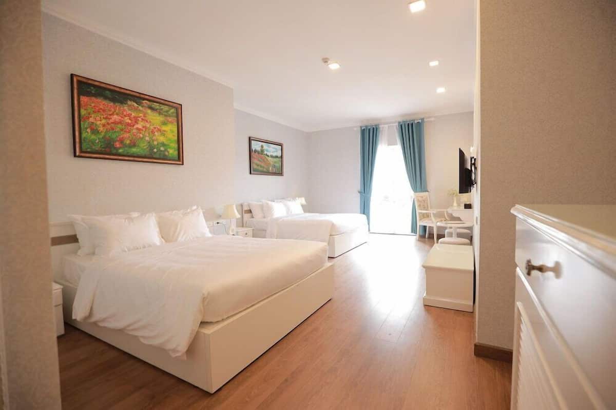 Quarto de hotel com cama, escrivaninha, cadeira e televisão.