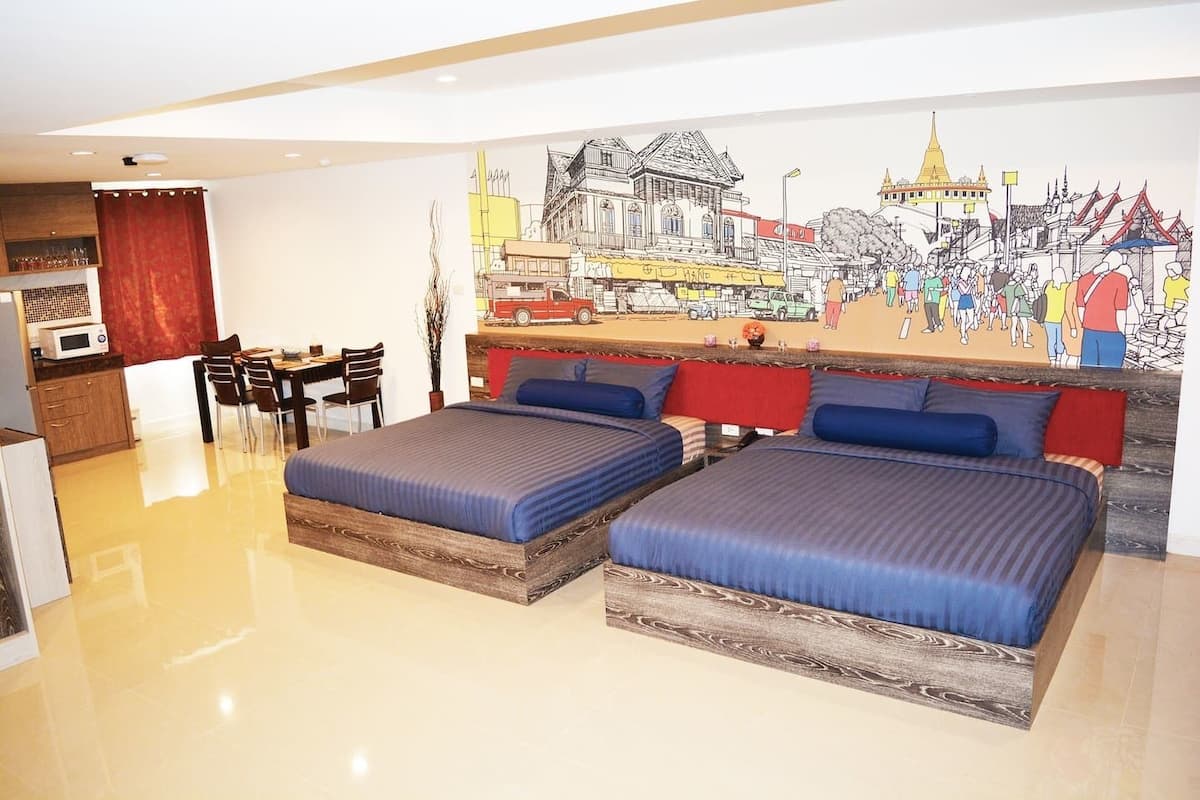 Une chambre d’hôtel avec deux lits, un coin repas et une fresque représentant un paysage urbain.