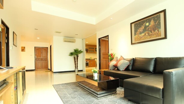 A modern living room with a black leather sofa, a glass coffee table, and a patterned rug. - Serena Sathorn Suites (Bangkok)