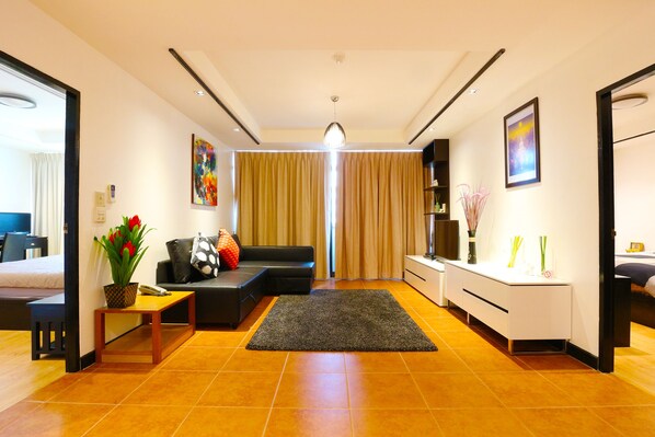 A modern living room with a sofa, a coffee table, and a rug. There is a desk with a vase and a picture frame.