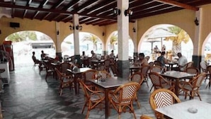 An indoor dining area with wooden tables and chairs, large windows, and a tiled floor. - Lemon Grove Hotel and Studios (Corfu)