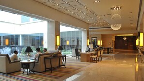 A spacious lobby with a seating area, large windows, and a modern chandelier. - Balaji Sarovar Premiere Solapur (Solapur)