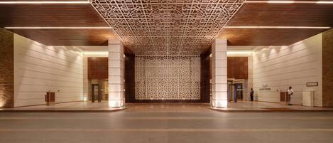 Un'ampia hall con un design geometrico del soffitto, una colonna centrale e una reception.