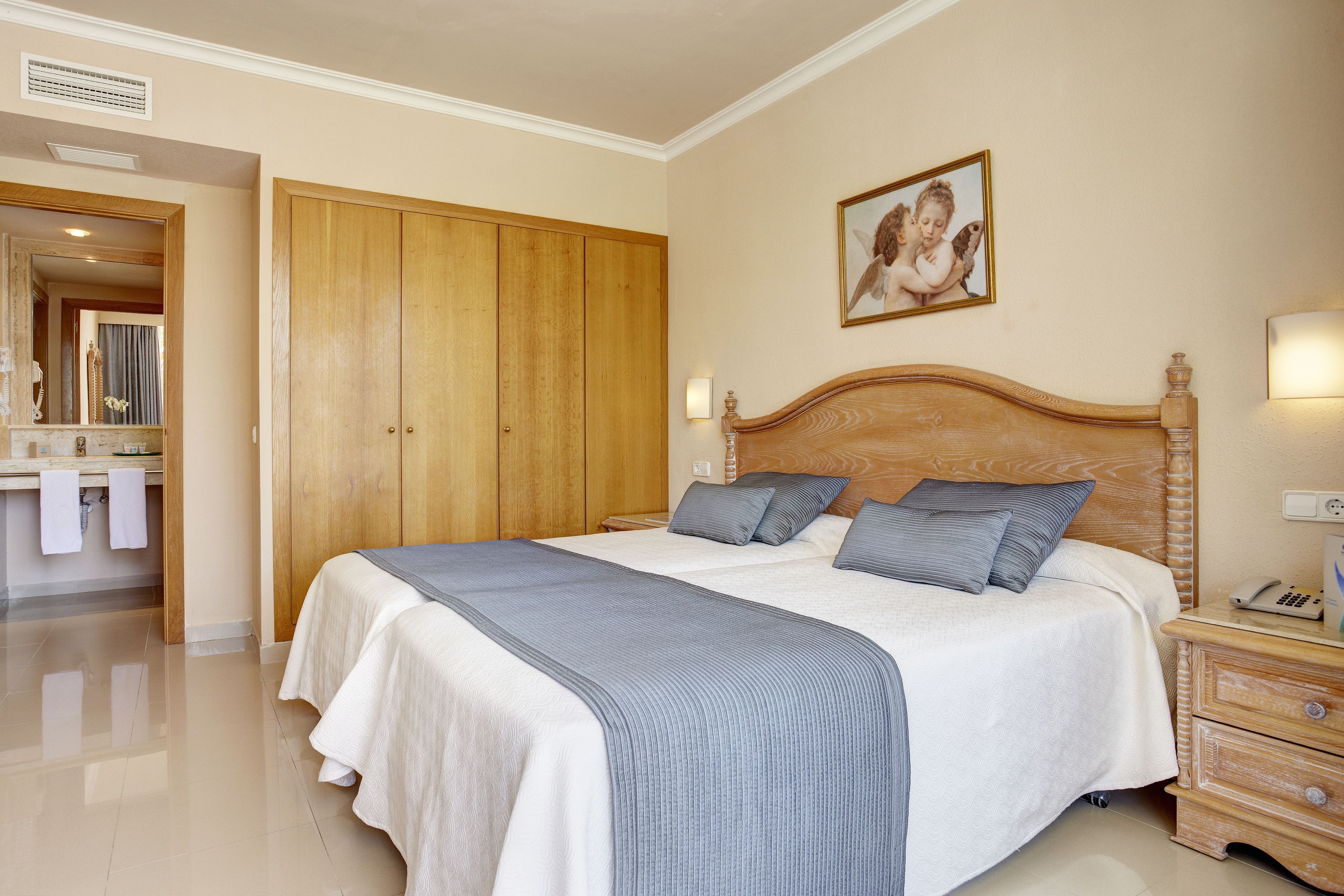 A bedroom with a large bed, wooden wardrobe, bedside table, and a mirror.