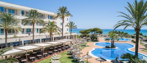 A resort with a pool area, outdoor seating, and a view of the ocean.