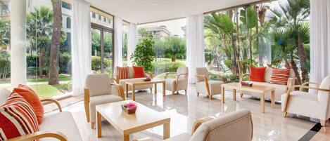 A spacious living area with multiple seating options, large windows offering a view of the outdoors, and a clean, modern design.