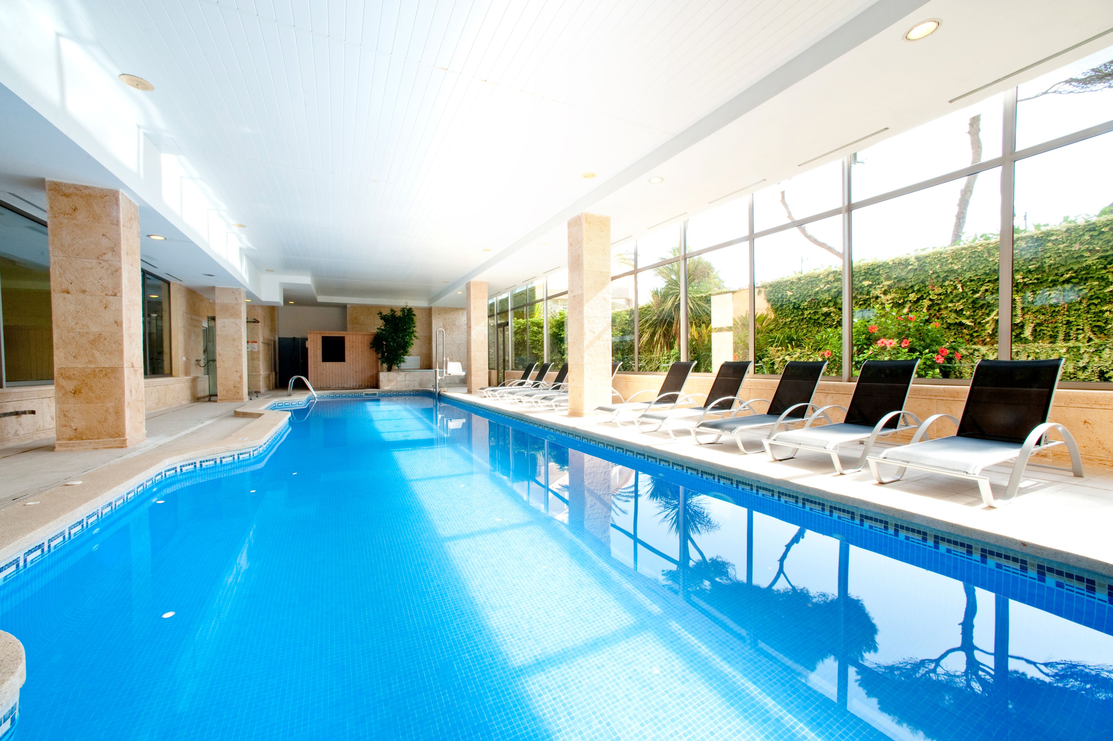 Una piscina con sillones de descanso y amplias ventanas.