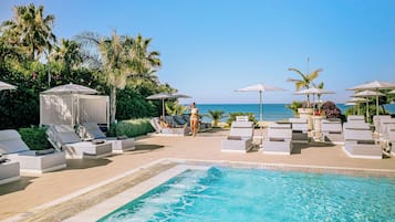 Una piscina techada, una piscina al aire libre, sombrillas