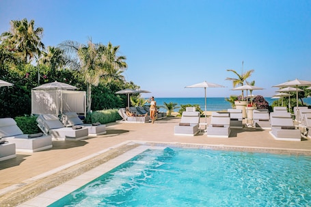 Una piscina techada, una piscina al aire libre, sombrillas