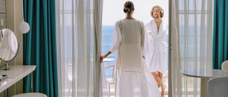 A hotel room with a balcony, a bed, a small table, and a mirror.