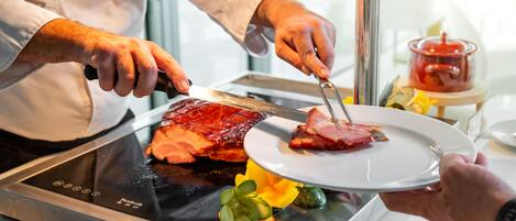 Una persona cortando carne en una parrilla, con un plato de verduras cerca.