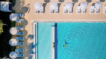 Una piscina cubierta, una piscina al aire libre, sombrillas, tumbonas