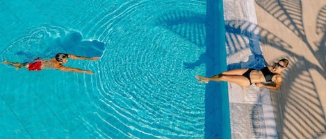 Una piscina techada, una piscina al aire libre, sombrillas