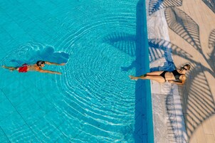 Una piscina techada, una piscina al aire libre, sombrillas